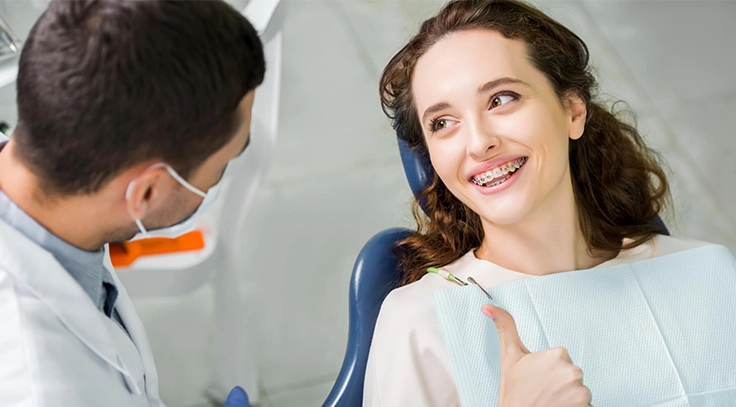 A smiling woman with braces is happy after correcting her misaligned teeth that affect her speech.