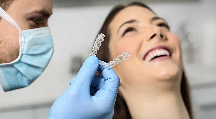 Dentist holding clear aligners while a patient smiles, showcasing an effective teeth-straightening.